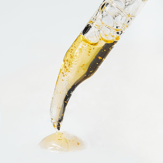 Closeup of dropper with yellow liquid with one drop on surface